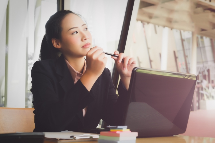 woman thinking in front of an open laptop computer
