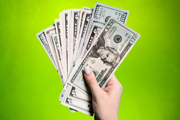 Woman looking at her phone a hand holds several currency bills