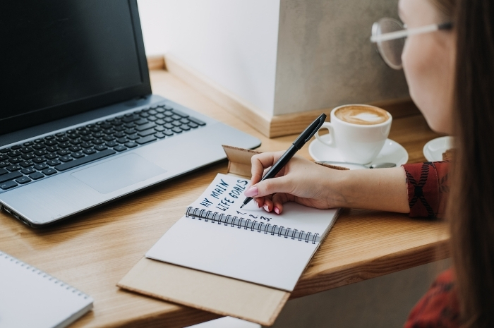woman writing life goals in a notebook