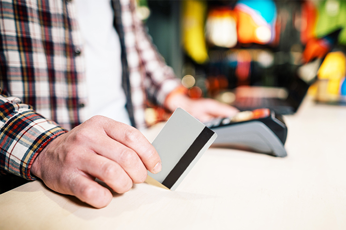 man in plaid shirt waiting to swipe his debit card