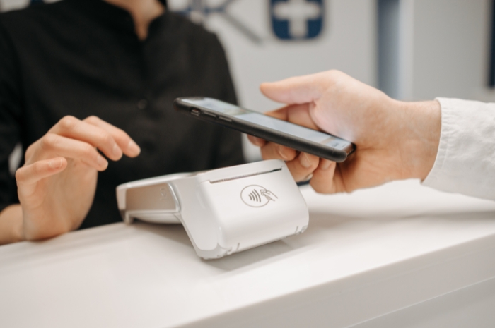holding a phone near a merchant terminal to pay with digital wallet