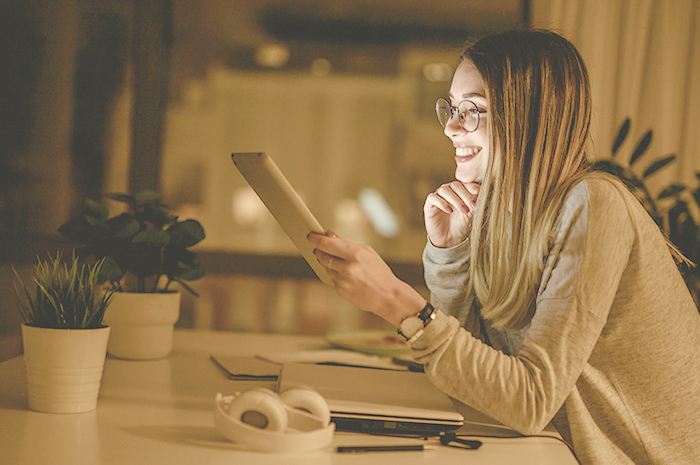 a young woman looks at a tablet late at night