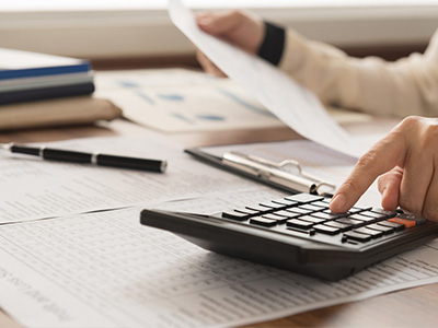 close-up of person using calculator while reviewing financial documents, signifying financial planning