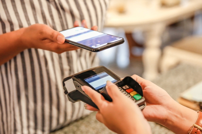 a person holding a smartphone near a merchant payment machine to use digital wallet
