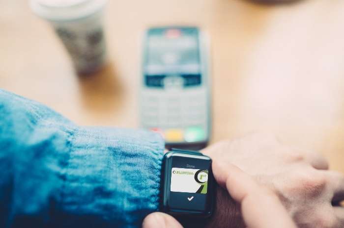 a smartwatch with a debit card image and a checkmark signifying successful payment
