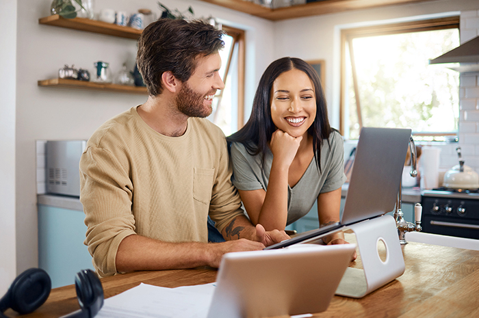 young couple smiles while looking at computer